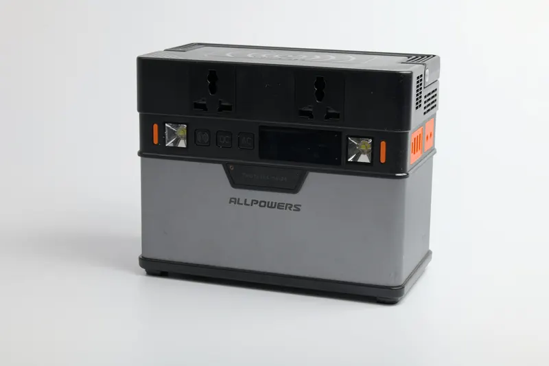 A compact portable power station with AC outlets and a carry handle on a white background